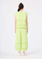 A person faces away, wearing the TREE PLEATS set by me ISSEY MIYAKE—a light green, sleeveless top and matching wide pants with hand pleating—styled with a ponytail and white slip-on shoes against a plain white background.