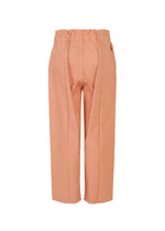 The FLAT DENIM SEASONAL pants by me ISSEY MIYAKE are high-waisted, ankle-length, loose-fit straight pants in salmon pink recycled polyester denim with visible seam details, shown against a white background.