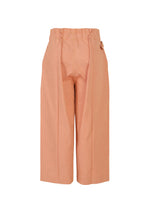 The FLAT DENIM SEASONAL pants by me ISSEY MIYAKE are salmon pink, high-waisted, cropped wide-leg pants with a paperbag waist, front pleats, side pockets, and a relaxed fit in recycled polyester denim.