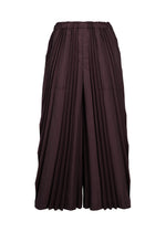The TOWER PLEATS BOTTOM by me ISSEY MIYAKE are wide-legged skirt-pants in a dark brown hue, showcasing handmade pleating and an elastic waistband, displayed against a plain white background. - BORDEAUX （no.84）