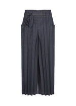 DENIM PLEATS BOTTOM by me ISSEY MIYAKE—dark gray, wide-leg trousers crafted from recycled polyester, featuring hand-pleated detailing, large side pockets, and a decorative belt at the waist, shown against a white background. - INDIGO （no.76）