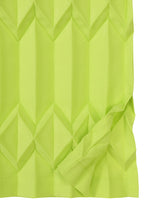 TREE PLEATS by me ISSEY MIYAKE is a vibrant yellow-green, textured fabric featuring a three-dimensional diamond pattern and a folded corner revealing the material’s underside.