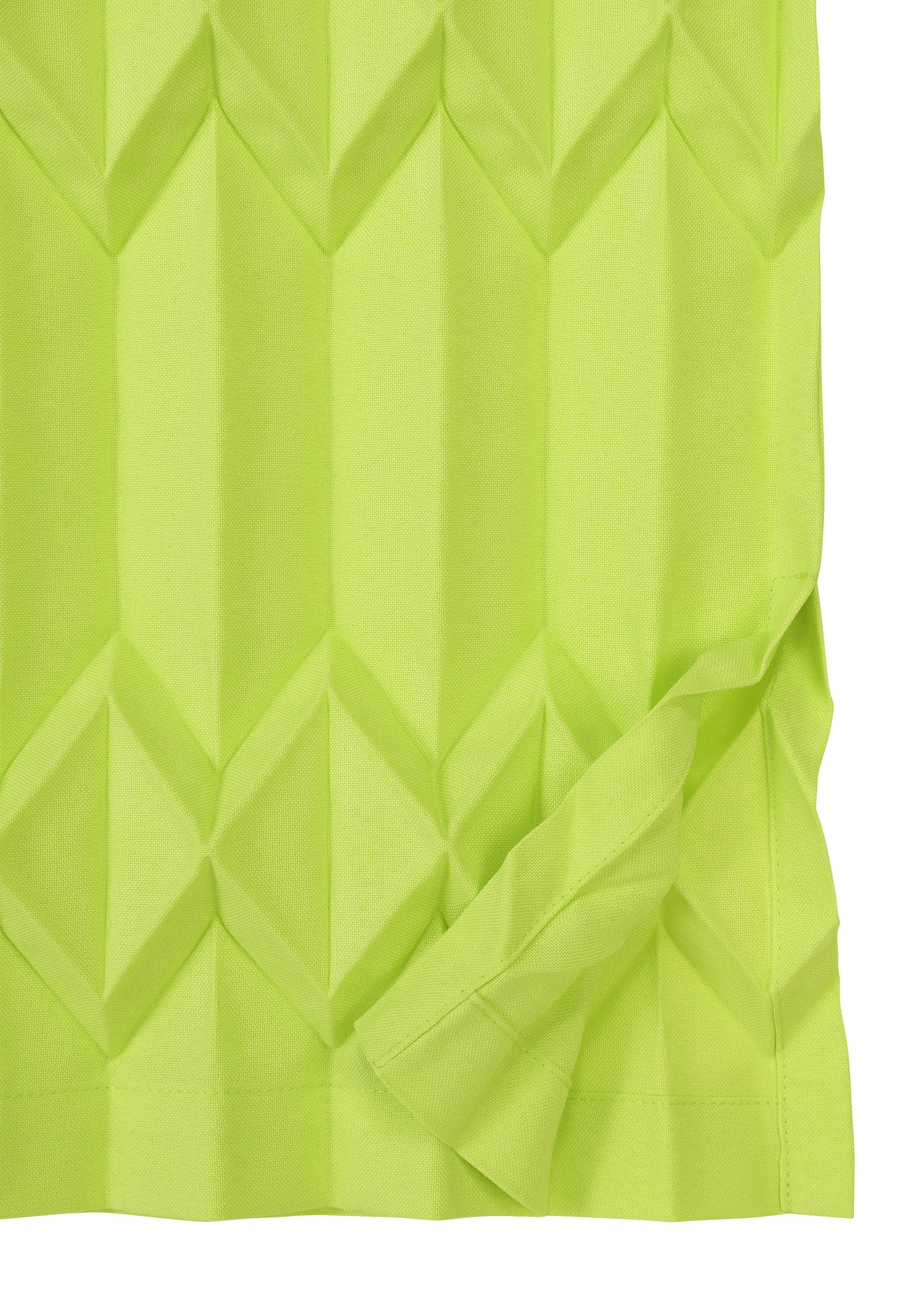 Zoomed view TREE PLEATS by me ISSEY MIYAKE is a vibrant yellow-green, textured fabric featuring a three-dimensional diamond pattern and a folded corner revealing the material’s underside.