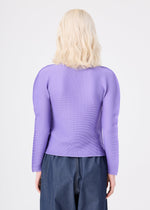 A person with shoulder-length blonde hair is seen from behind, wearing the me ISSEY MIYAKE STRETCH PLEATS 3 long-sleeved, high-neck top paired with high-waisted blue jeans against a plain white background.