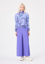 A person with light hair wears the “PLANT” high-neck long-sleeve stretch pleats top by me ISSEY MIYAKE, featuring a subtle plant pattern in light blue, paired with wide-legged pleated lavender pants and white shoes, standing against a plain white background.