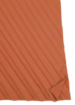 A burnt orange, diagonally striped fabric with a folded lower right corner reveals intricate texture and stitching details—ideal for crafting the ANGLE PLEATS SHIRT from me ISSEY MIYAKE, a versatile piece that emphasizes both style and comfort.