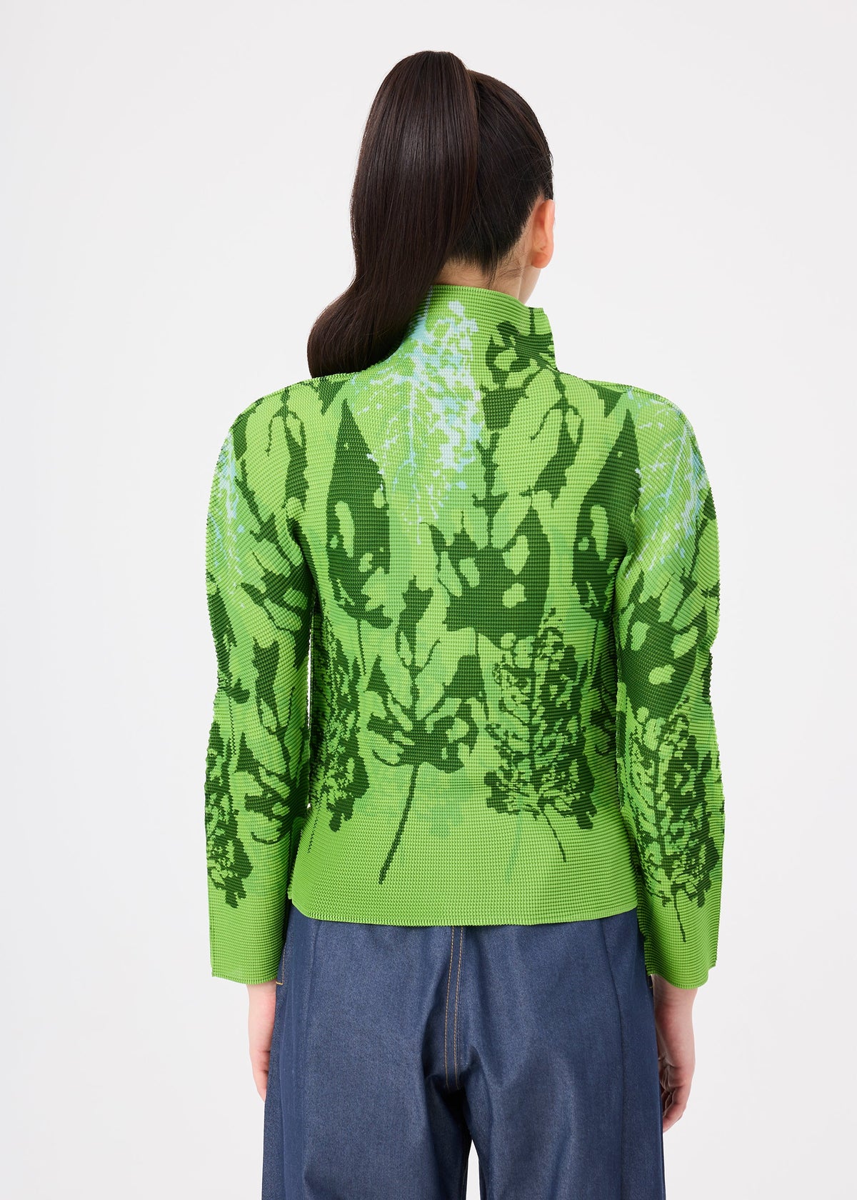 A person with long dark hair in a ponytail wears the LEAF shirt by me ISSEY MIYAKE and blue jeans, facing away from the camera against a plain white background. view 6 of 7
