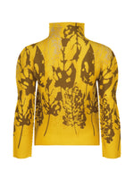 The LEAF top by me ISSEY MIYAKE is a yellow high-neck, long-sleeve piece featuring brown abstract leaf patterns, displayed on a white background.