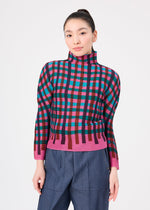 A woman with long dark hair in a ponytail wears the TAPE CHECK top by me ISSEY MIYAKE and blue high-waisted pants, standing against a plain white background.