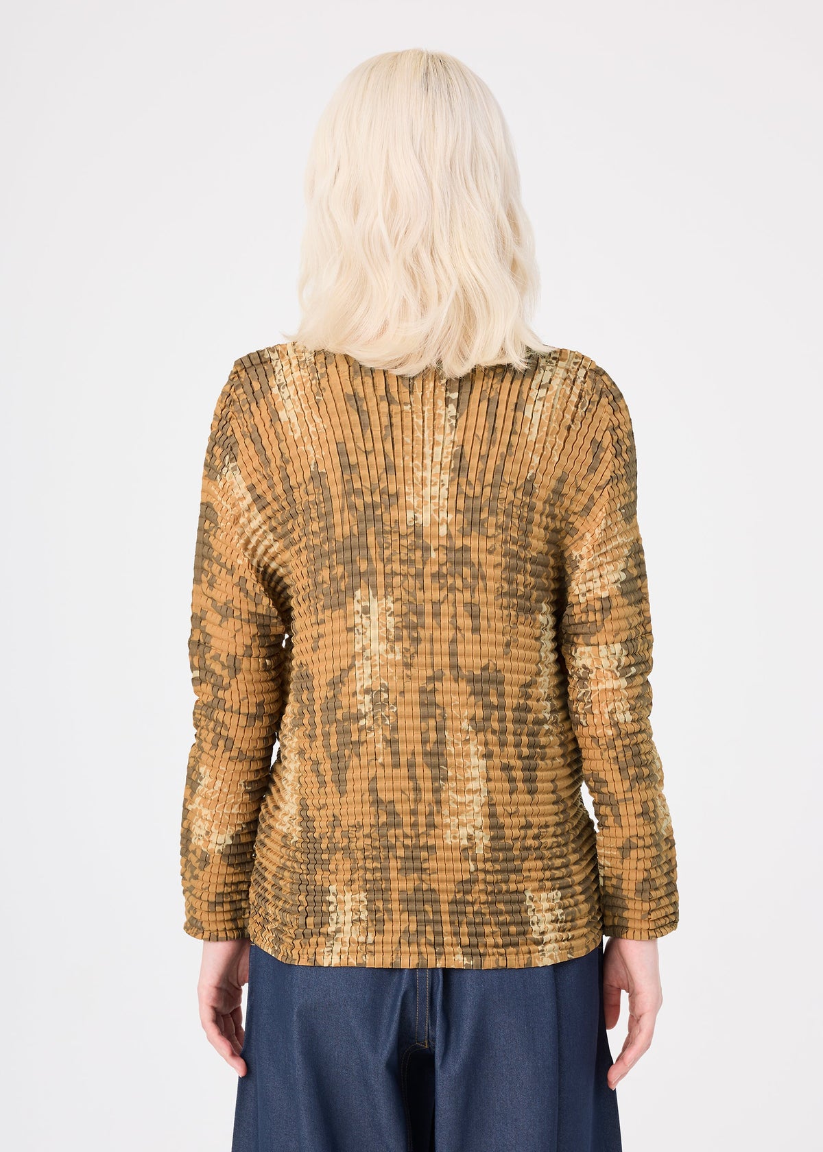 A person with wavy, shoulder-length blonde hair wears the LEAF PLEATS SHIRT by me ISSEY MIYAKE in gold and brown, styled with dark pants, shown from the back against a plain white background. view 6 of 7