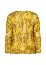 The image shows the back of the LEAF PLEATS SHIRT by me ISSEY MIYAKE, a yellow pleated long-sleeve top with a crinkled texture and an abstract brown and white pattern.