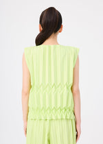A person with long dark hair in a ponytail is shown from the back, wearing the TREE PLEATS sleeveless top and matching pants by me ISSEY MIYAKE, featuring hand-pleated three-dimensional patterns against a plain white background.