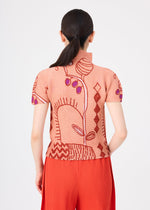 A woman with dark hair in a low ponytail models the me ISSEY MIYAKE “PLANT” top—a peach-colored, high-neck, short-sleeve stretch pleats piece adorned with abstract red and purple plant motifs—paired with red pleated pants, standing with her back to the camera against a white background.