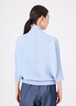 A woman with straight, dark hair in a low ponytail is seen from behind wearing the me ISSEY MIYAKE DOLMAN STRETCH PLEATS 1 light blue three-quarter sleeve top and dark blue pants, set against a plain white background.