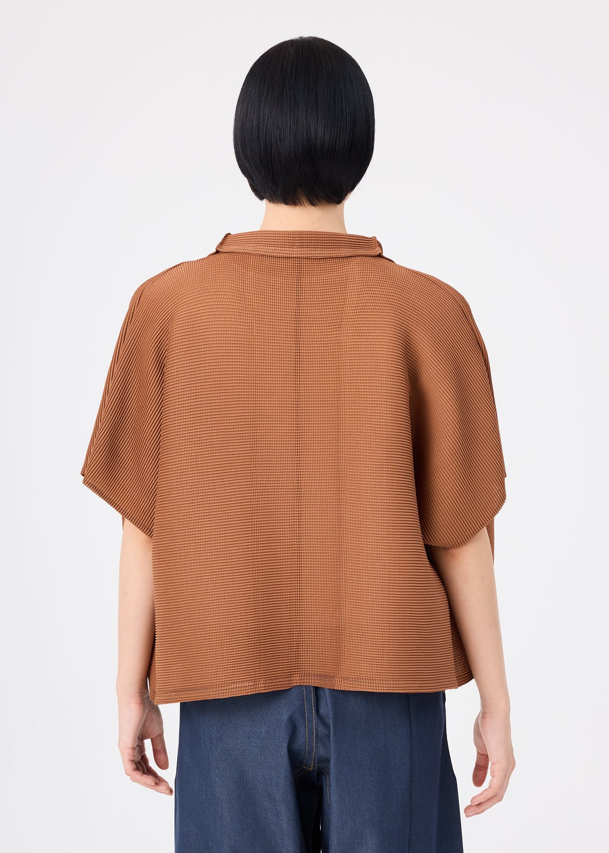 A person with short black hair stands with their back to the camera against a plain white background, wearing the me ISSEY MIYAKE SQUARE STRETCH PLEATS relaxed-fit brown short-sleeved cardigan paired with blue jeans. view 8 of 10