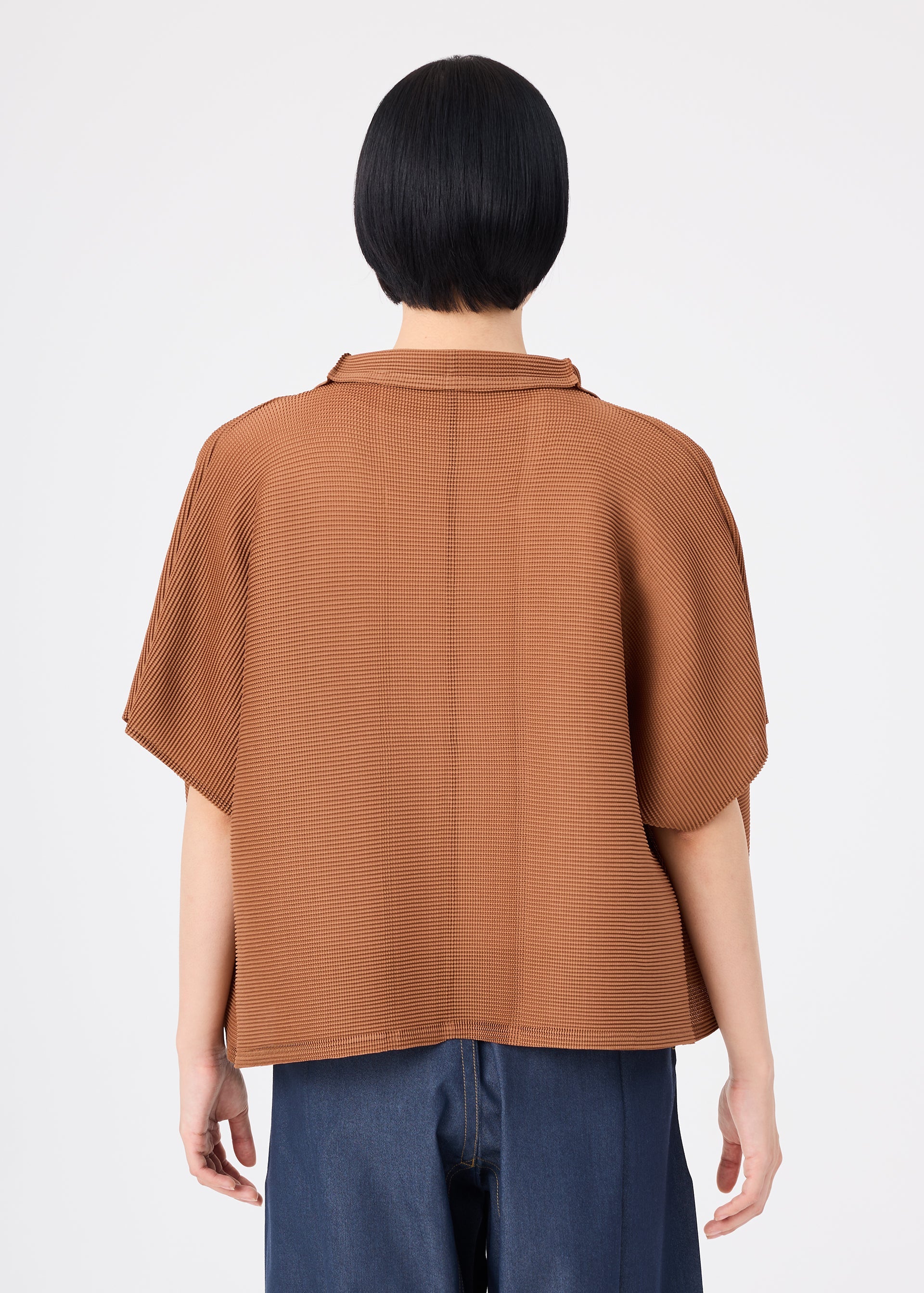 Zoomed view A person with short black hair stands with their back to the camera against a plain white background, wearing the me ISSEY MIYAKE SQUARE STRETCH PLEATS relaxed-fit brown short-sleeved cardigan paired with blue jeans.