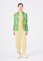 A woman faces forward wearing the LEAF PLEATS SHIRT by me ISSEY MIYAKE over a yellow turtleneck, yellow pleated pants, and white shoes against a plain white background.