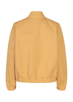 A back view of the me ISSEY MIYAKE PINA CLOTH jacket in mustard yellow, garment-dyed with a simple collar, long sleeves, and an elastic waistband.