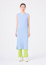 A person faces forward with a neutral expression, wearing the me ISSEY MIYAKE SEE-THROUGH CREPE COLOR dress in light blue over bright lime green pleated pants and white shoes, standing against a plain white background.