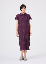 A person with short dark hair wears the SHRINK STRIPE knee-length cotton-blend dress by me ISSEY MIYAKE in a textured purple design with short sleeves, paired with light-colored shoes, standing against a plain white background.