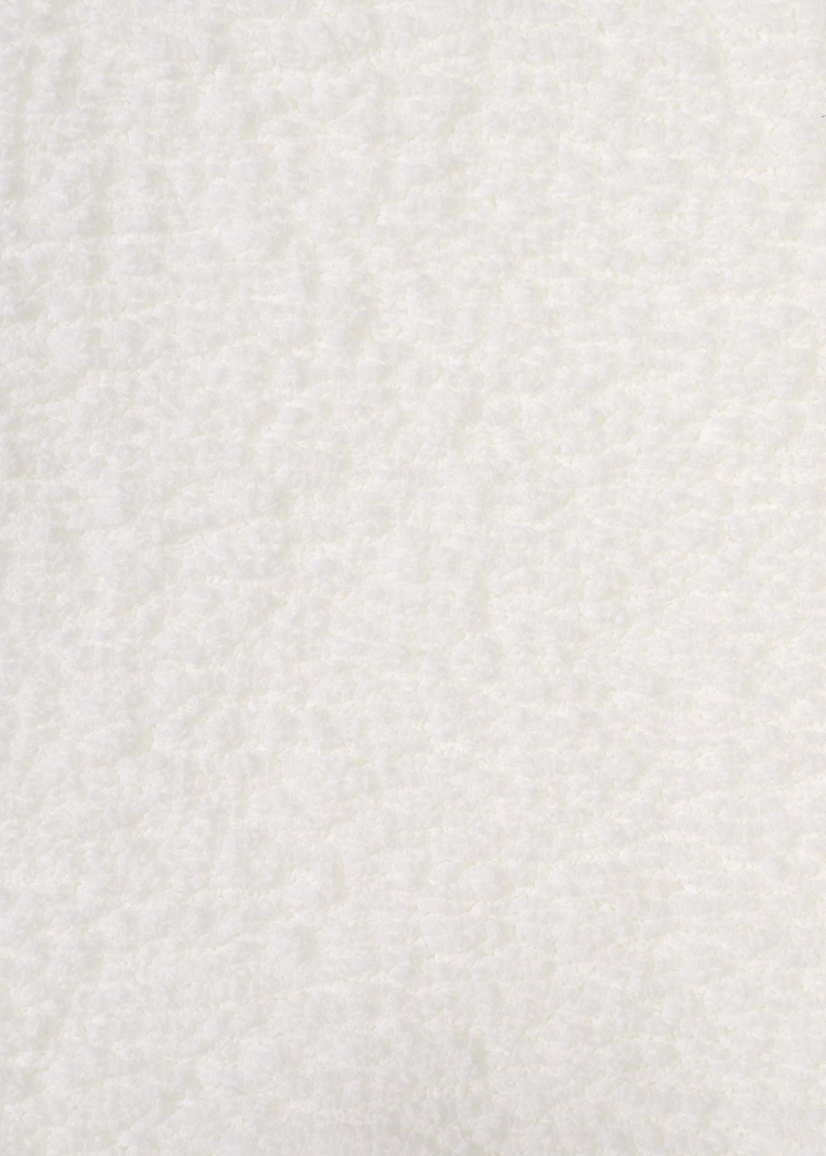 Close-up of the white, soft, and fluffy textured surface of the CAULIFLOWER top by me ISSEY MIYAKE. The plush texture is evenly distributed, with subtle shadows and highlights across the material—evoking the cozy feel of this short-sleeved, round-neck garment. view 4 of 7
