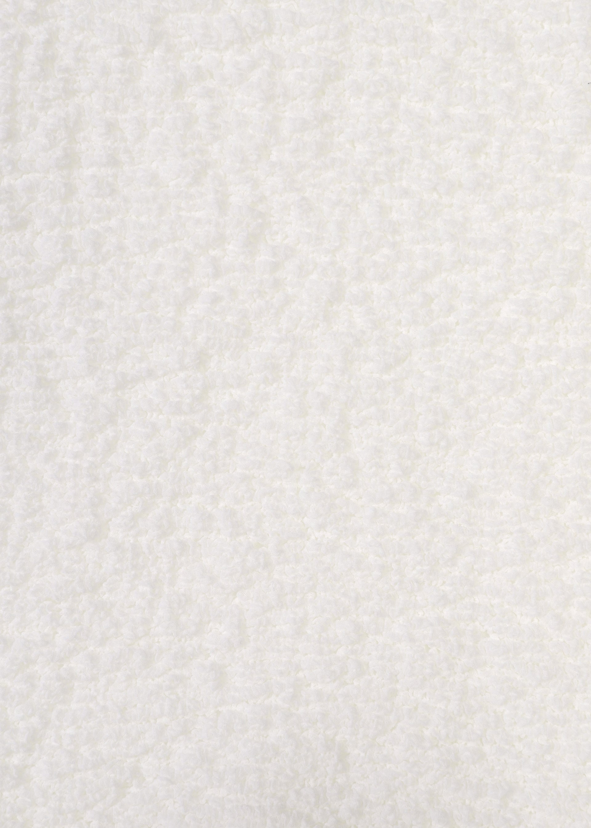 Zoomed view Close-up of the white, soft, and fluffy textured surface of the CAULIFLOWER top by me ISSEY MIYAKE. The plush texture is evenly distributed, with subtle shadows and highlights across the material—evoking the cozy feel of this short-sleeved, round-neck garment.