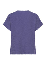 The LEAF TULLE CAULIFLOWER top by me ISSEY MIYAKE is displayed from the back, featuring short sleeves and a textured purple cotton fabric. Its relaxed, square silhouette and soft, fluffy material provide a loose and comfortable fit with no visible patterns or embellishments.