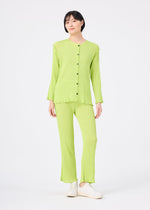 A person stands against a white background wearing the me ISSEY MIYAKE SEE-THROUGH CREPE COLOR set: a light green, long-sleeved, button-up top with matching green pants and white shoes.