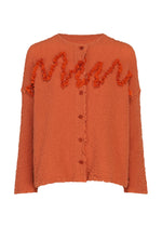 A vibrant orange cotton cardigan by me ISSEY MIYAKE, the LEAF TULLE CAULIFLOWER, features long sleeves and wavy ruffle detailing across the chest and arms, capturing the playful elegance of a cauliflower-inspired design. - VERMILION （no.34）
