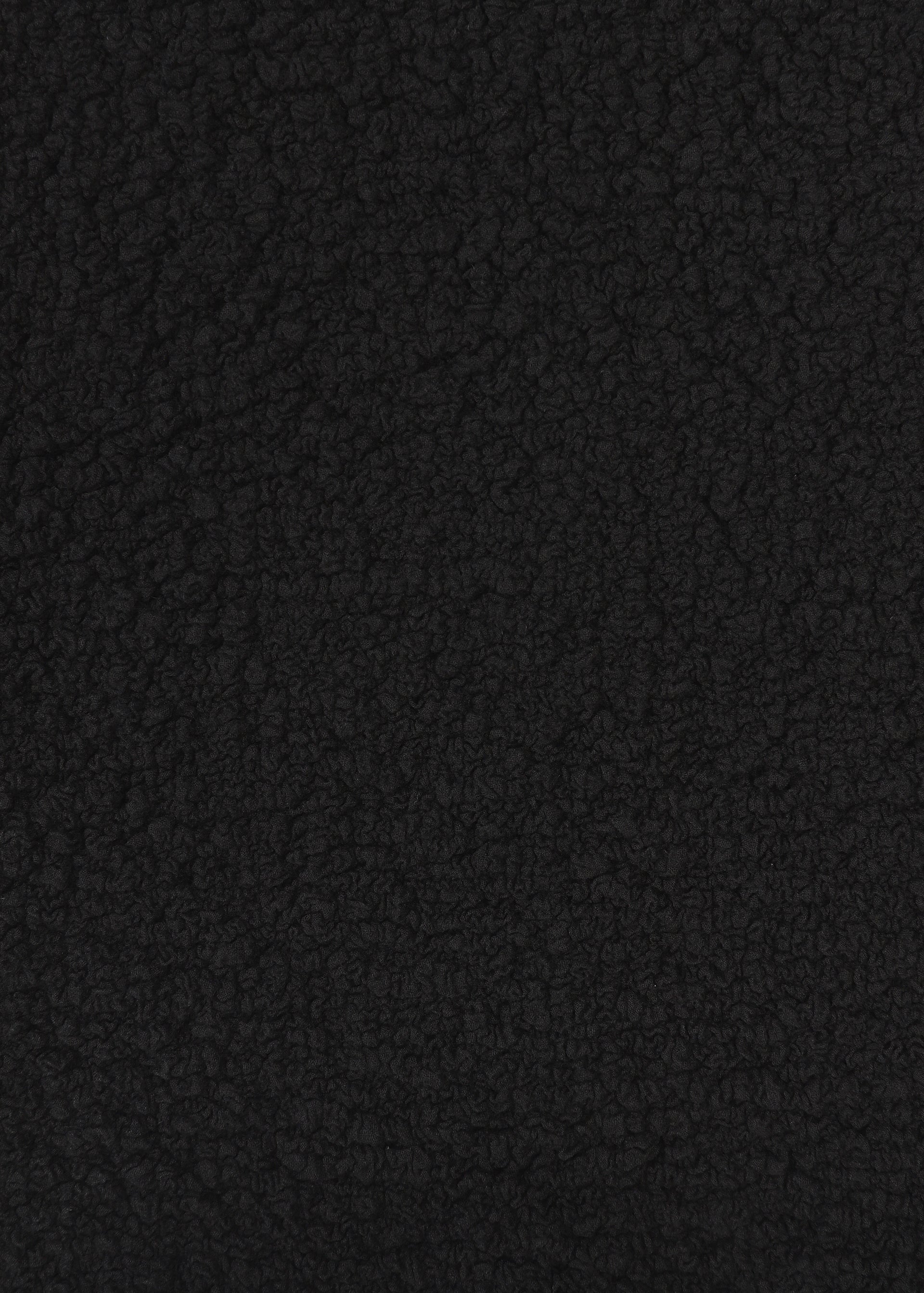 Zoomed view Close-up of CAULIFLOWER by me ISSEY MIYAKE—a textured, black material with a soft, bumpy surface reminiscent of fleece or sherpa—highlighting its cozy appeal in a cotton round-neck top.