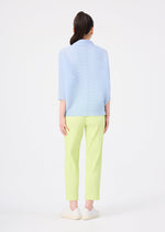 A woman stands facing away against a white background, wearing the FINE KNIT PLEATS COLOR 1 top in light blue with elbow-length sleeves by me ISSEY MIYAKE, paired with pale yellow straight pants and white slip-on shoes. Her hair is tied in a high ponytail.