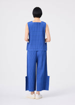 A person with short black hair stands facing away against a plain white background, wearing a sleeveless blue top and the FINE KNIT PLEATS BOTTOM 1 by me ISSEY MIYAKE—wide pleated knit pants featuring unique side panels—paired with white slip-on shoes.