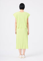 A person with short black hair is standing facing away, wearing the me ISSEY MIYAKE MESH PLEATS light green, short-sleeved, knee-length pleated knit skirt dress and white slip-on shoes, against a plain white background.