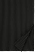 A piece of black FINE KNIT PLEATS fabric by me ISSEY MIYAKE, with one corner folded upward to reveal the textured underside. The soft material features fine, evenly spaced vertical knit ridges.