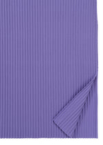 A sheet of corrugated paper in a rich purple, featuring vertical ridges and partially folded at the bottom right corner to reveal its texture and flexibility—evoking the delicate structure of the FINE KNIT PLEATS COLOR 2 dress by me ISSEY MIYAKE.