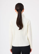 A woman with long, straight dark hair in a low ponytail is seen from behind, wearing the FINE KNIT PLEATS top by me ISSEY MIYAKE and black pants against a plain white background.
