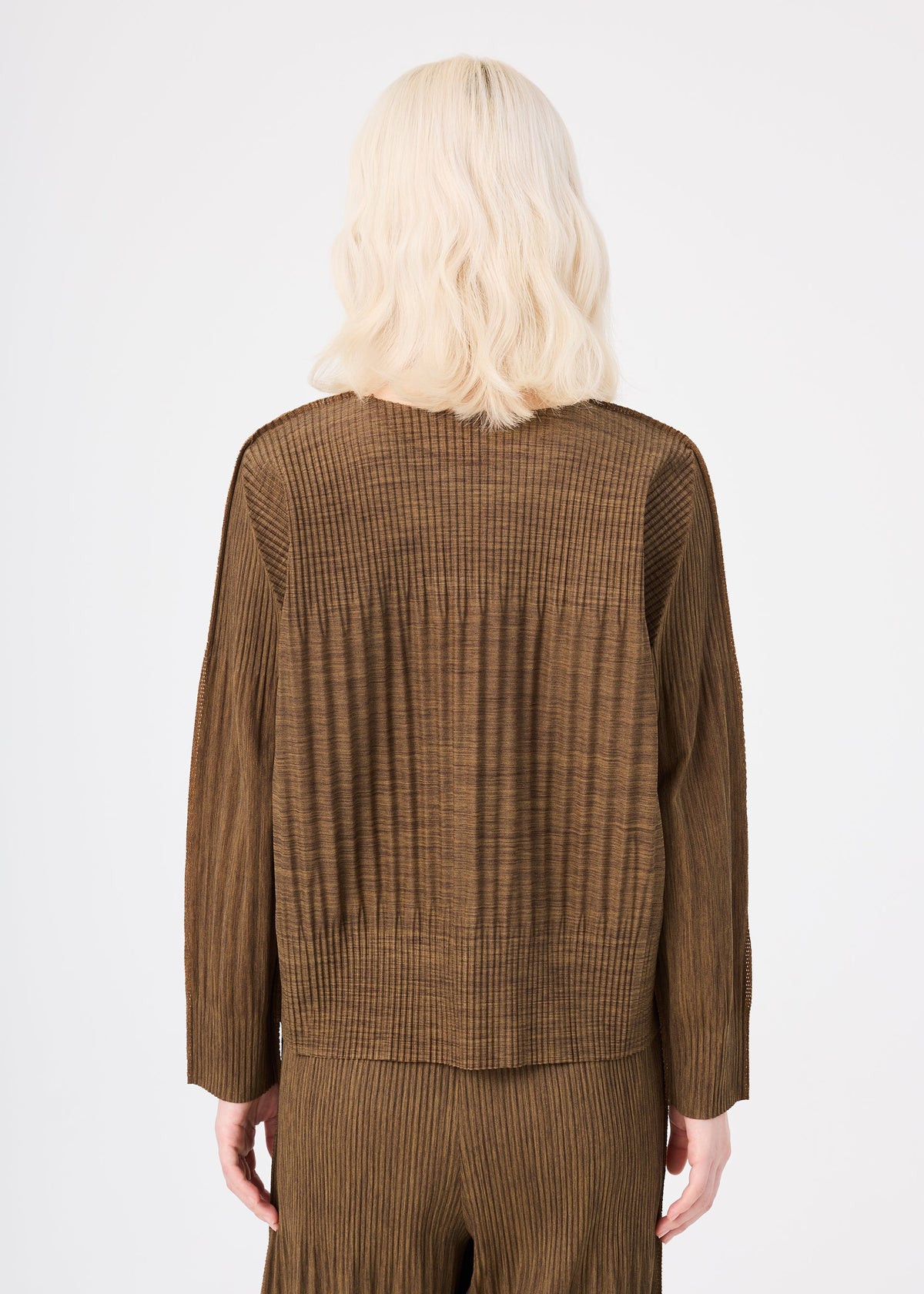 Zoomed view A person with wavy, shoulder-length blonde hair models the MIX FINE KNIT PLEATS from me ISSEY MIYAKE, a ribbed brown long-sleeved top and matching pleated pants, seen from the back against a white background.