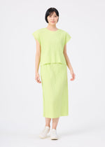 A person faces forward against a white background, wearing the MESH PLEATS light green short-sleeved top and matching midi skirt with fine knit pleats and vertical ribbing by me ISSEY MIYAKE, paired with white slip-on shoes.