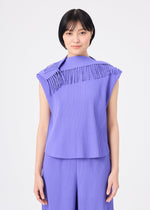 A person with short black hair stands against a plain white background, facing forward and smiling slightly while wearing the LEAF PLEATS sleeveless set by me ISSEY MIYAKE—a lightweight ensemble featuring pleated lavender fabric with fringe details and matching pants.