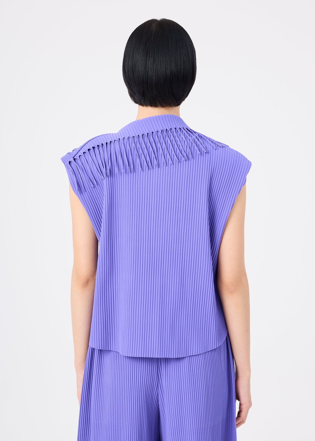 A person with short black hair is seen from behind against a plain white background, wearing the me ISSEY MIYAKE LEAF PLEATS set—a sleeveless, fine-knit pleated lavender top paired with matching pants. view 6 of 8