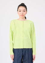 A person with long dark hair tied back is wearing the me ISSEY MIYAKE FINE KNIT PLEATS COLOR 1 cardigan and dark wide-leg pants, standing against a plain white background.