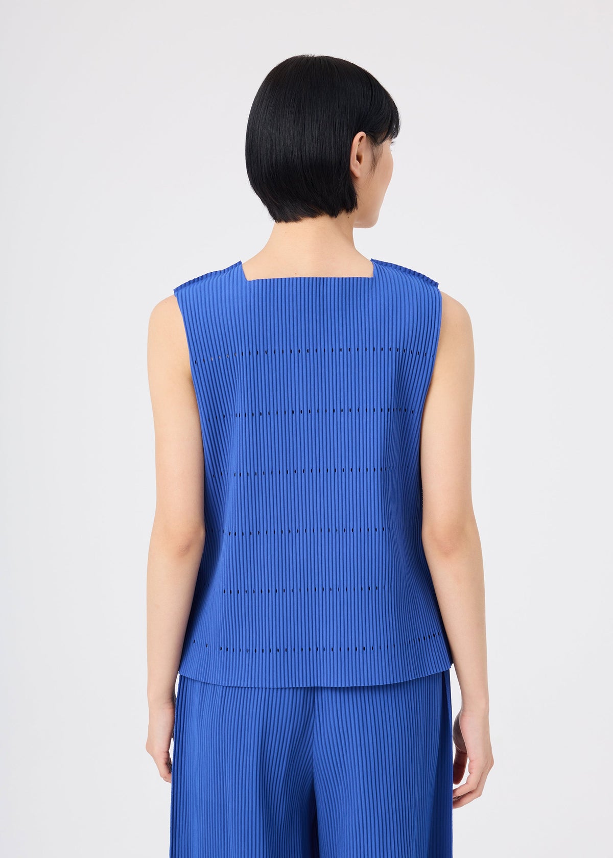 A person with short black hair is shown from the back against a plain light background, wearing the me ISSEY MIYAKE TOWER PLEATS sleeveless pleated knit blue top and matching pants. view 6 of 7