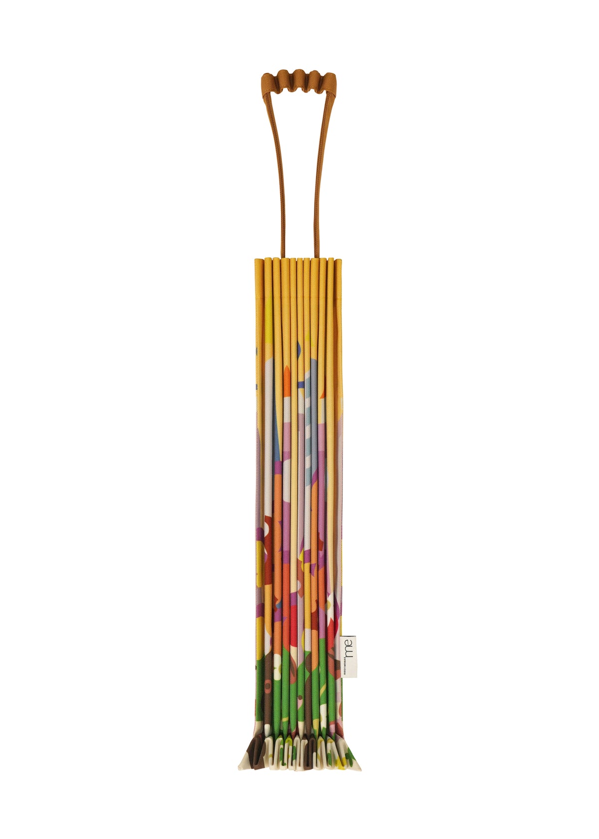 A colorful, pleated TRUNK PLEATS BAG / NY by me ISSEY MIYAKE with a geometric, multicolored pattern and a small branded tag stands upright against a plain white background. view 2 of 6