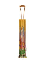 A colorful, pleated TRUNK PLEATS BAG / NY by me ISSEY MIYAKE with a geometric, multicolored pattern and a small branded tag stands upright against a plain white background. - YELLOW-HUED （no.59）