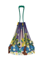 The TRUNK PLEATS BAG / NY by me ISSEY MIYAKE features a whimsical floral and bear pattern, green string handles, and a side fabric tag—perfect for a stroll in Madison Square Park.