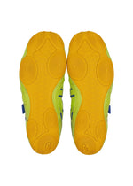 The HYPER TAPING sneakers by ISSEY MIYAKE FOOT are shown from below, displaying yellow rubber outsoles with circular and wavy patterns, plus green and blue accents on the sides—highlighting the brand’s bold design.