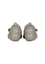 A pair of light gray HYPER TAPING sneakers by ISSEY MIYAKE FOOT seen from the back, with green heel logos and pull tabs that recall athletic taping—a signature ISSEY MIYAKE FOOT-inspired detail.