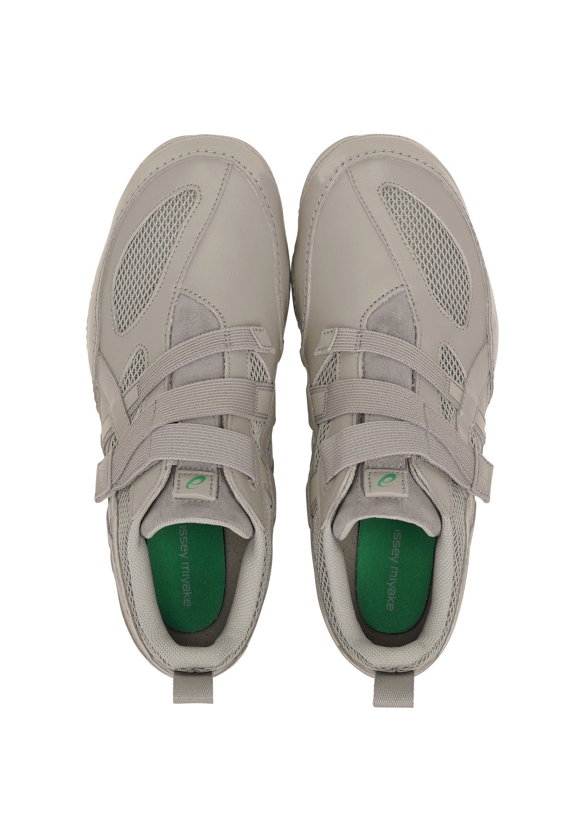 Zoomed view A pair of light gray ISSEY MIYAKE FOOT HYPER TAPING sneakers with mesh and leather details, green insoles and laces, viewed from above on a white background.