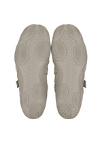 The soles of ISSEY MIYAKE FOOT's HYPER TAPING sneakers in light gray, with circular and wavy patterns inspired by athletic taping, are shown from the bottom against a white background.