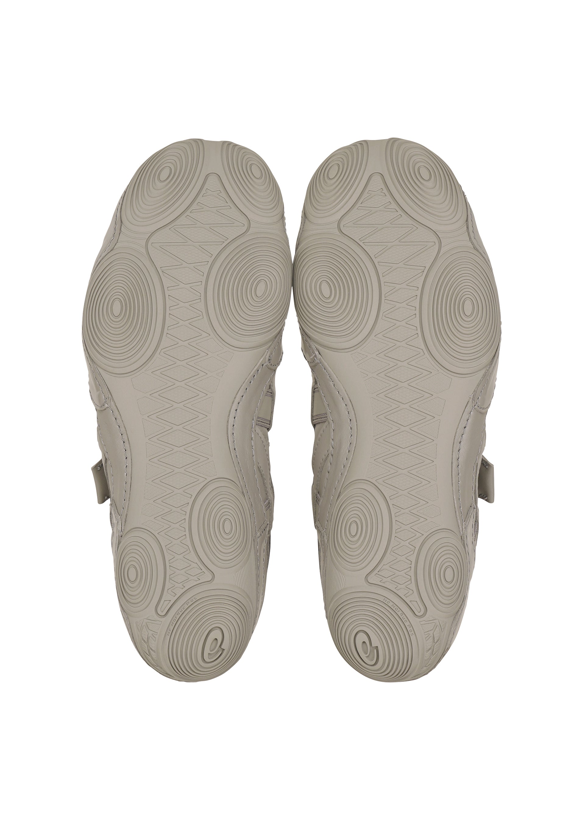 Zoomed view The soles of ISSEY MIYAKE FOOT's HYPER TAPING sneakers in light gray, with circular and wavy patterns inspired by athletic taping, are shown from the bottom against a white background.